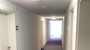 A hallway with patterned carpet, white walls, and doors on both sides. - Wohnung in Neckarwestheim by Interhome (Neckarwestheim)