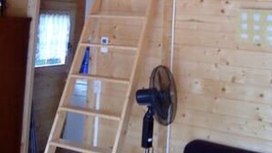 Ein Holzinnenraum mit Schlafgalerie, einer Leitern und einem Ventilator.