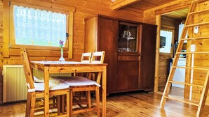 Ein Holzinterieur mit Esstisch, Stühlen, einem Schrank und einer Leiter.