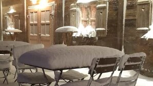 An outdoor seating area with a table and chairs covered in snow, under string lights. - Schöndorf by Interhome (Tholey)