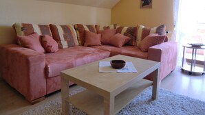 Un soggiorno con un divano rosa, un tavolino in legno e un piccolo tavolo con una ciotola.