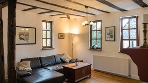 A cozy living room with a dark leather sofa, wooden coffee table, and exposed wooden beams on the ceiling. - in Traben mit Kleinem Garten by Interhome (Traben-Trarbach)