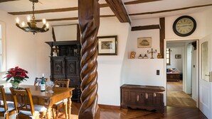 A dining area with a wooden table, chairs, and a chandelier. There is a wooden cabinet and a clock on the wall. - in Traben mit Kleinem Garten by Interhome (Traben-Trarbach)