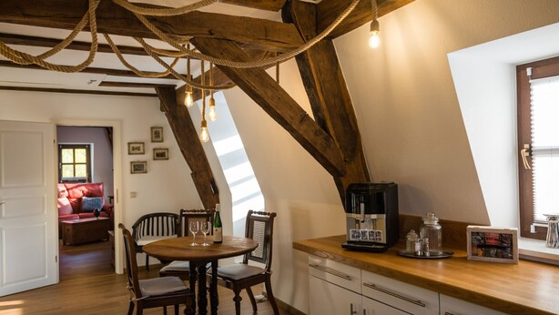 A dining area with a wooden table, chairs, and a coffee machine. There is a window with blinds and a door leading to another room. - in Traben mit Kleinem Garten by Interhome (Traben-Trarbach)