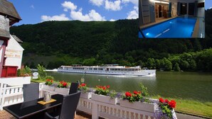 Ein Flusskreuzfahrtschiff mit Essbereich, der Korbmöbel und Blumenbeete zeigt.
