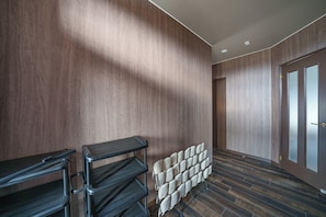 A modern hotel room with a wooden wall, a black metal desk, a chair, and a radiator.