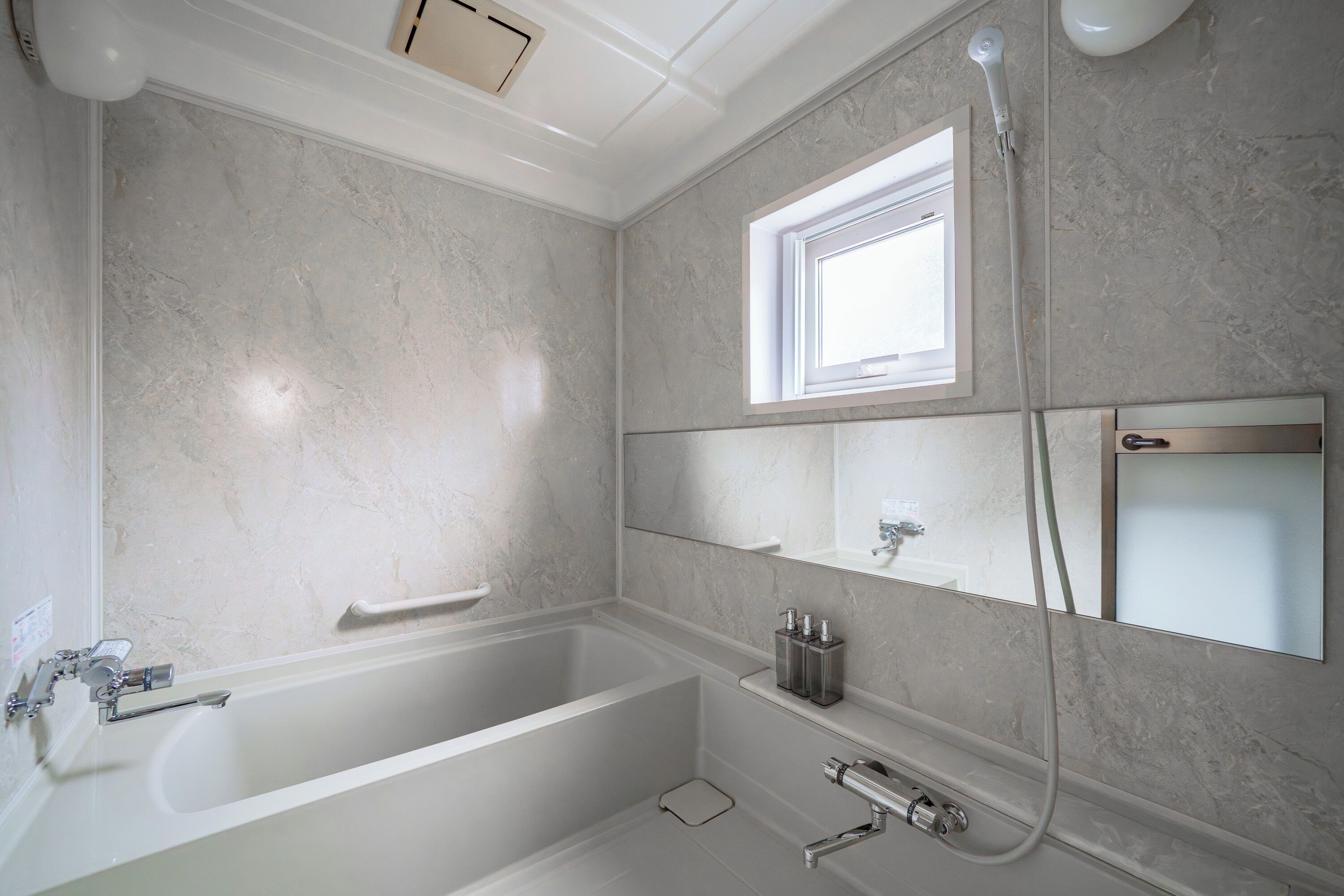 A modern bathroom with a freestanding bathtub, a window, and a mirror.