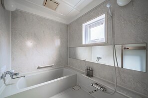 A modern bathroom with a freestanding bathtub, a window, and a mirror.