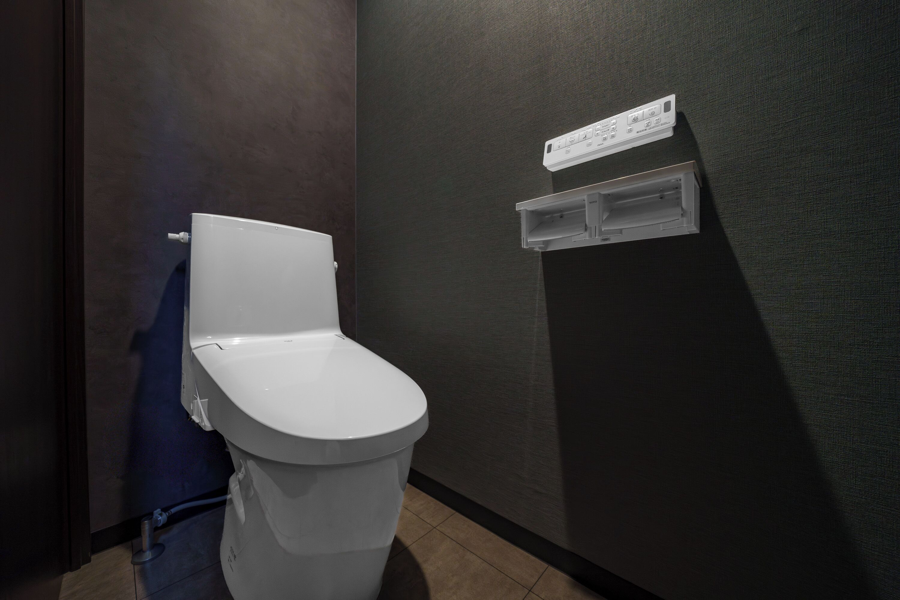 Un baño moderno con un inodoro blanco, un perchero y un estante pequeño con un letrero.