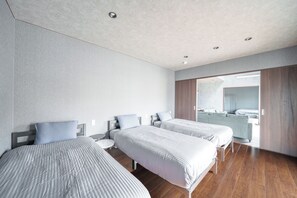 A modern hotel room with two single beds, a wooden floor, and a large mirror on the wall.