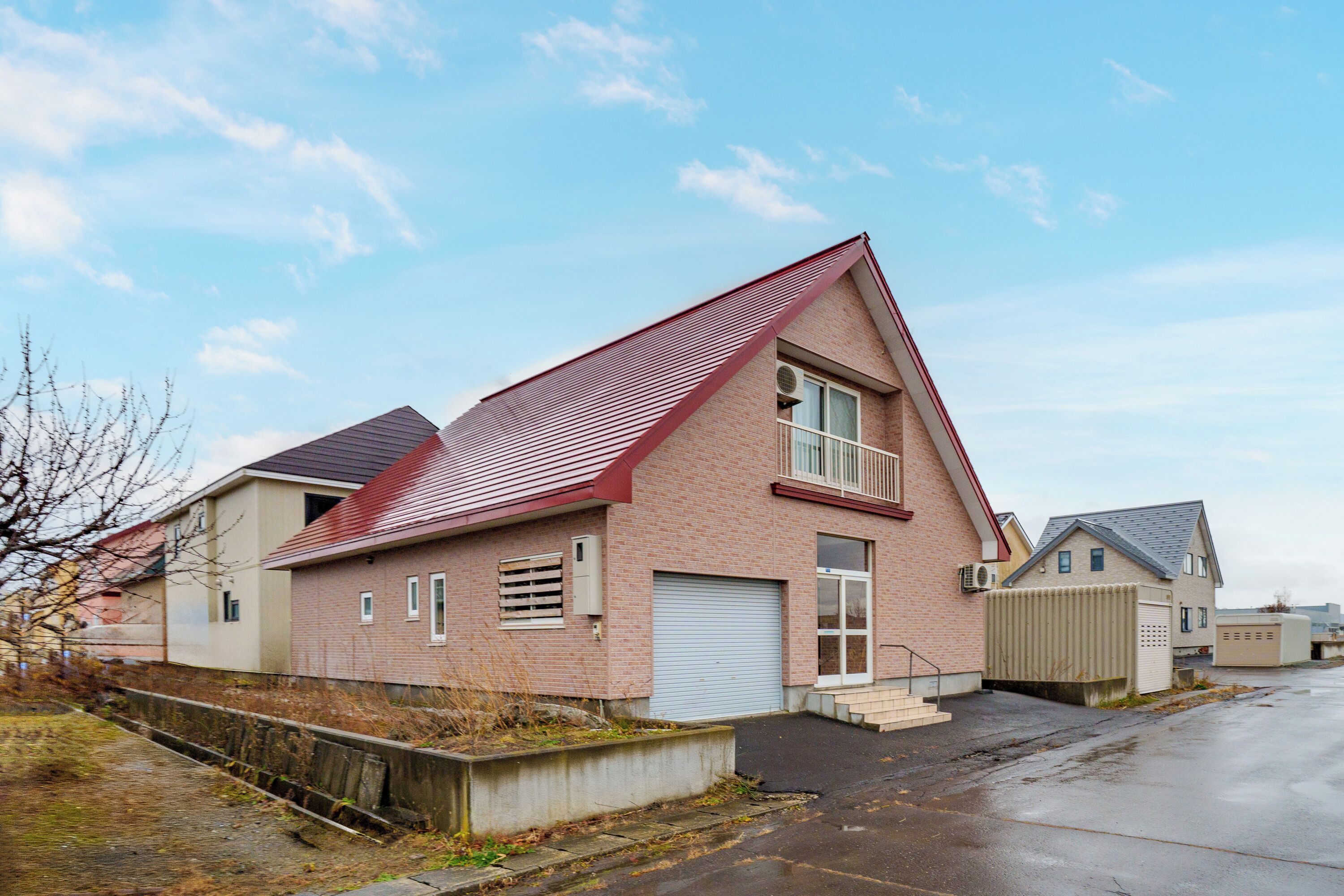 A residential building with a red roof, brick exterior, and a garage door.