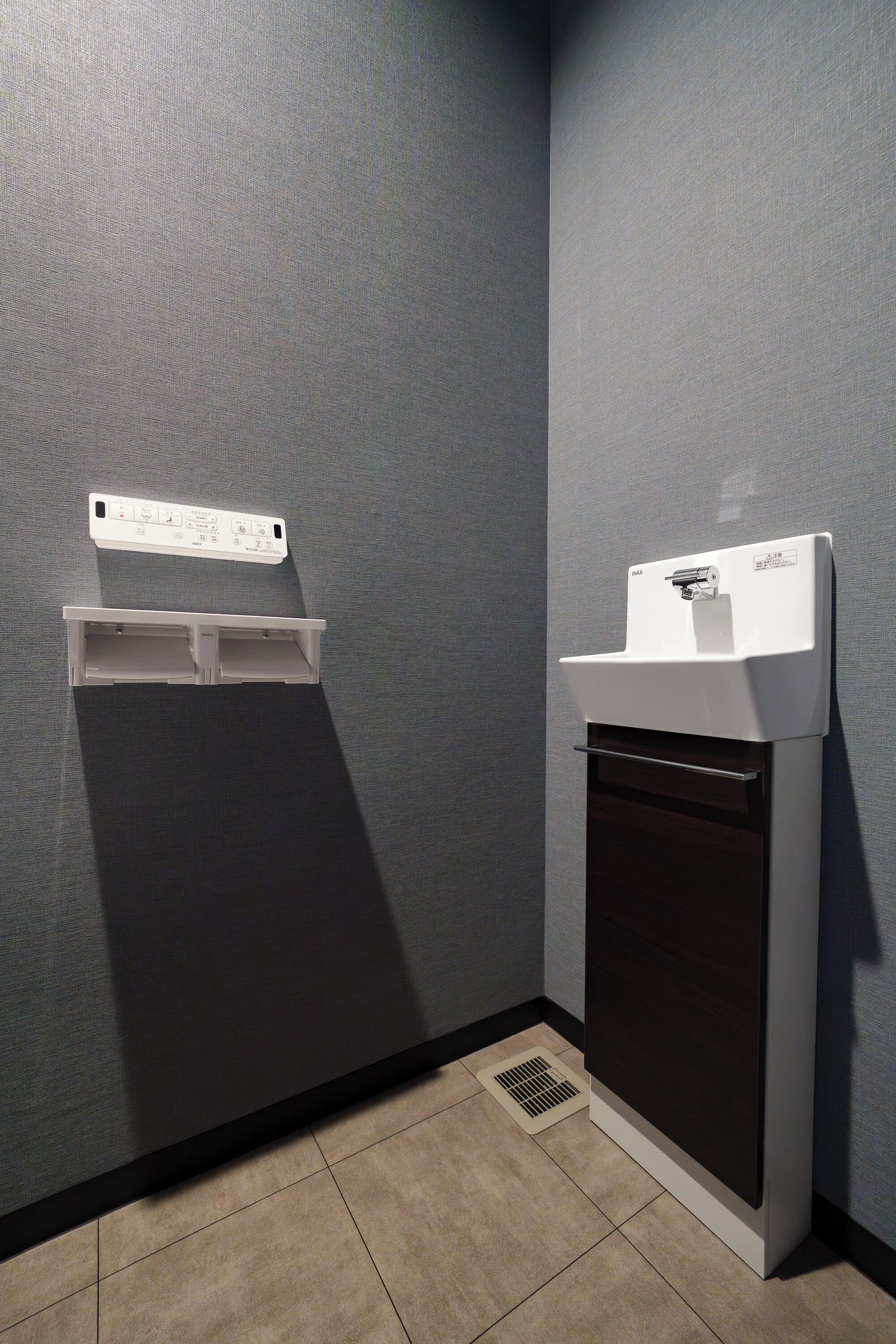 Une salle de bain avec un lavabo blanc, un miroir et une prise électrique murale.