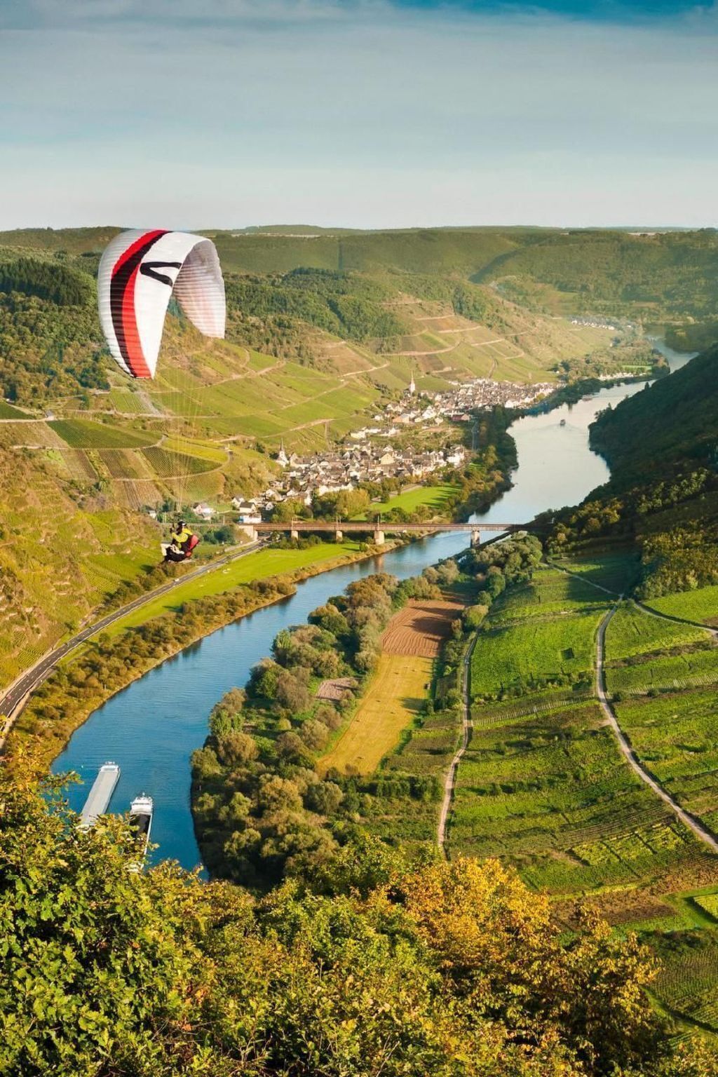 Een schilderachtig luchtbeeld van een rivierdal met een stad, wijngaarden en een brug.