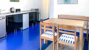 Une cuisine compacte dotée d’appareils électroménagers modernes, un coin repas avec des meubles en bois et des œuvres d’art accrochées aux murs.