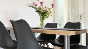 Ein Essbereich mit Holztisch, schwarzen Stühlen und einem Blumenstrauß.