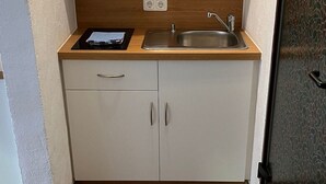 Kompakti keittiö, jossa on sisäänrakennettu liesi, pesuallas ja puinen työtaso.
