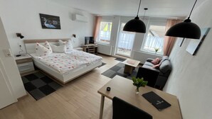 Et moderne hotelværelse med seng, skrivebord, stol, fjernsyn og et vindue med gardiner.
