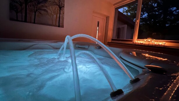 A hot tub with a ladder, a painting of trees, and a window with lights. - Ober Langengarten by Interhome (Pittenbach)