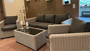 A living room with a grey sofa, a wicker coffee table, and wall-mounted picture frames. - Ober Langengarten by Interhome (Pittenbach)