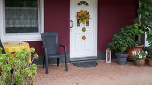 A front door with a flower wreath, a chair, and potted plants. - Apartment Im Hof by Interhome (Pittenbach)