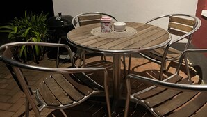A round wooden table with metal chairs, a decorative container, and a small white object on the table. - Apartment Im Hof by Interhome (Pittenbach)