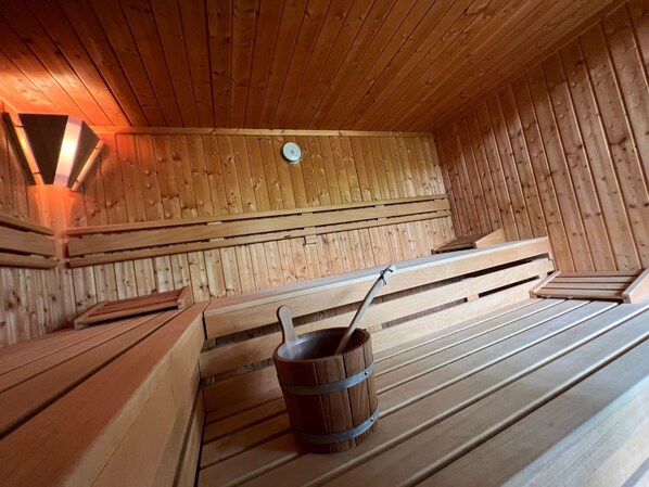Una sauna con panche di legno e un catino.
