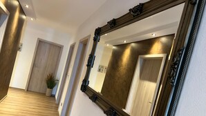 A hallway with wooden flooring, a large ornate mirror, and wooden doors. - Suite am Radweg by Interhome (Pittenbach)