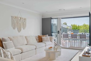 Una sala de estar moderna con sofá, mesa de centro y vista al patio exterior.
