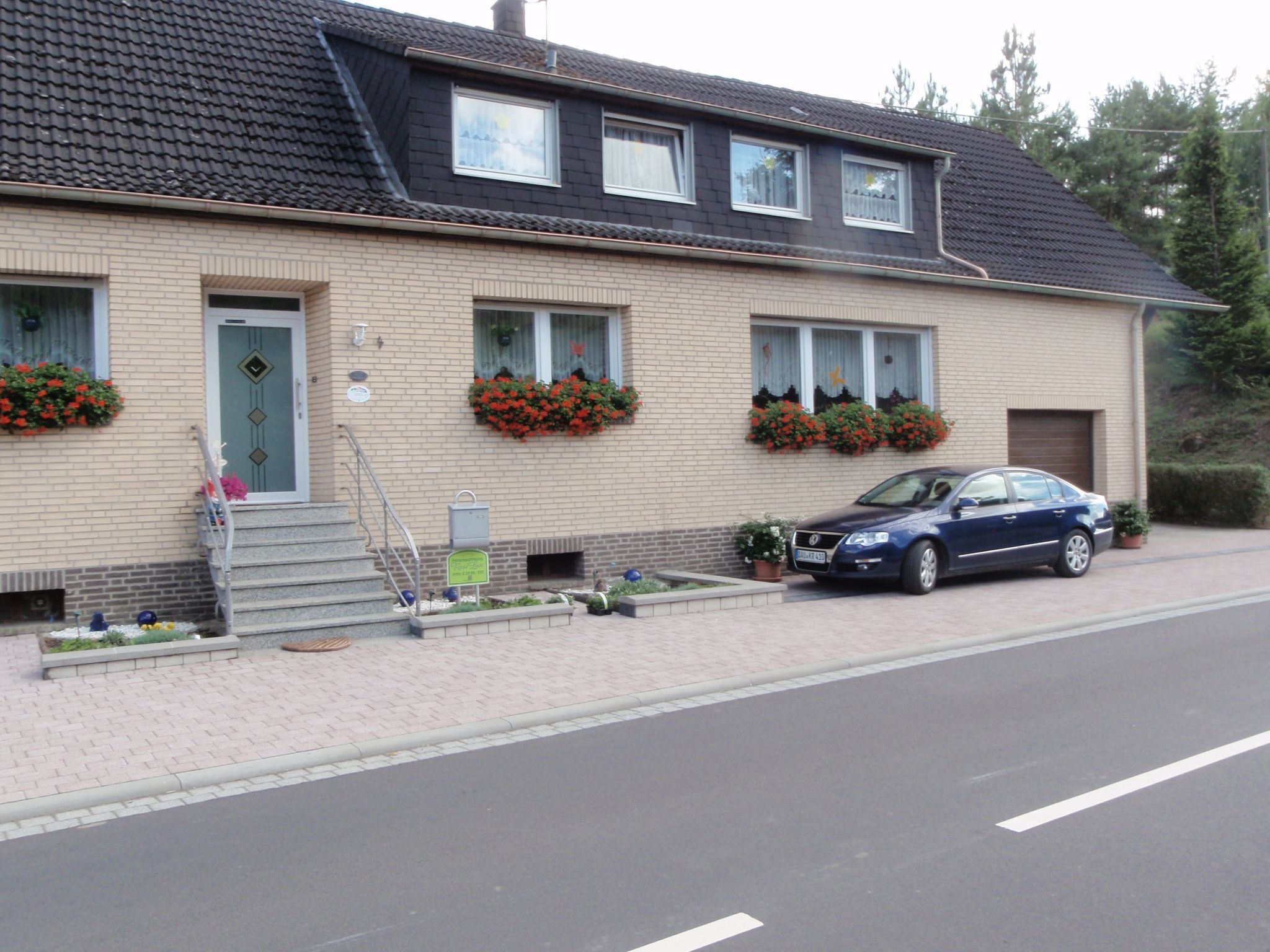 Une maison à deux étages avec une voiture garée dans l’allée.
