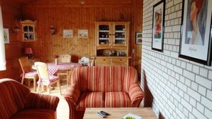 A cozy cabin interior with wooden walls, a dining area with a table and chairs, and a sofa. - Haus Sonnenhang by Interhome (Esch)