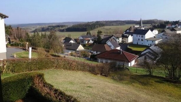A rural village with white houses, a church, and a large open field. - Haus Sonnenhang by Interhome (Esch)