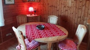 A wooden dining room with a round table, red and white checkered chairs, and wall-mounted light fixtures. - Haus Sonnenhang by Interhome (Esch)