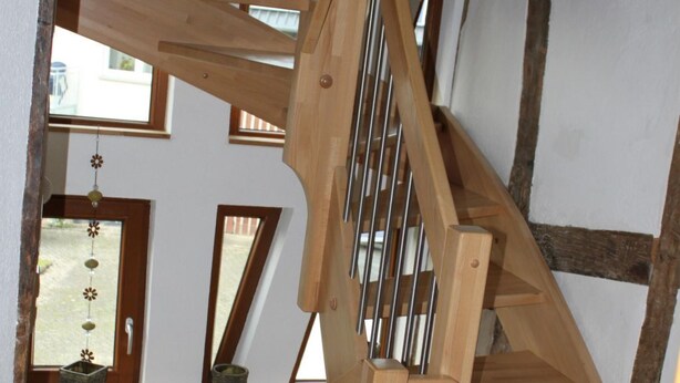 Un escalier en bois donnant sur une pièce avec une fenêtre et une porte.
