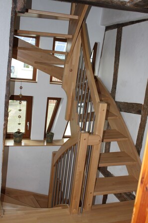 Een houten trap met uitzicht op een kamer met een raam en een deur.