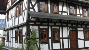 Une maison traditionnelle à colombages, dotée de nombreuses fenêtres et d’une porte.