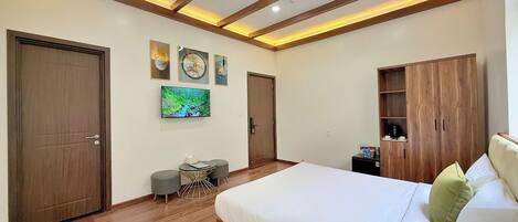 Un dormitorio moderno con una cama grande, suelo de madera, televisor y estanterías empotradas de madera.