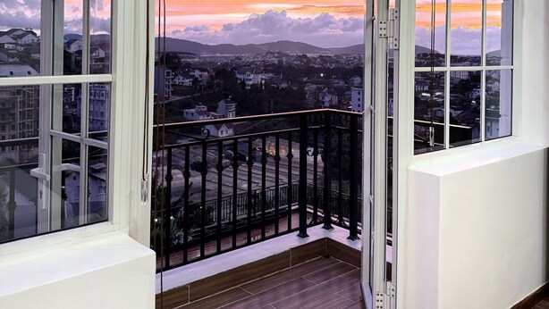 A balcony with a view of a cityscape and mountains during sunset. - KIEN DALAT (Lam Vien - Da Lat)