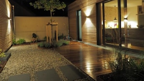 A modern building with a wooden exterior, a paved patio with stepping stones, and a small tree. - Exklusives Ferienhaus mit Terrasse und Garten by Interhome (Simmerath)