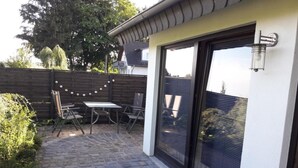 Eine Terrasse mit Tisch und Stühlen, ein Holzzaun und Blick ins Viertel.