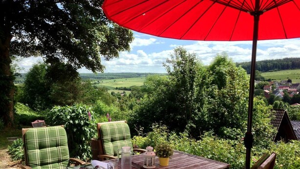 An outdoor seating area with a table, chairs, and a red umbrella. - Belle Vue by Interhome (Husen)