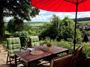 An outdoor seating area with a table, chairs, and a red umbrella. - Belle Vue by Interhome (Husen)