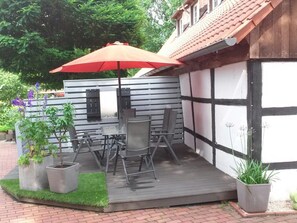 A patio with a table and chairs, a red umbrella, and potted plants. - An der Königstrasse by Interhome (Tecklenburg)