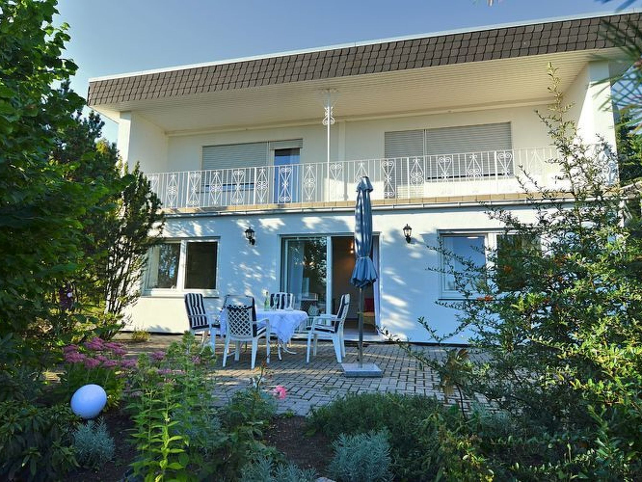 A two-story building with a balcony, outdoor seating area, and a garden.