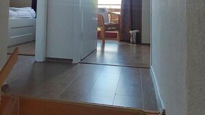 A hallway leading to a bedroom with a bed, a chair, and a small table. - Charmantes Ferienhaus mit Blick auf den Silberse by Interhome (Frielendorf)