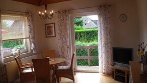 Un salón acogedor con comedor, televisión y vistas a un jardín.