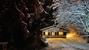 Ett snötäckt landskap med ett hus som är upplyst av ett varmt ljus.