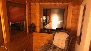 Une pièce chaleureuse avec un fauteuil en osier, une décoration en forme d’étoile et une affiche accrochée au mur.