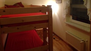 A small, single-bed room with a wooden bunk bed, a radiator, a window with blinds, and a framed picture on the wall. - mit Terrasse by Interhome (Blankenburg)