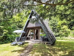 A triangular wooden cabin with a patio area, a covered seating area, and a view of the surrounding forest. - mit Garten, Grill und Terrasse by Interhome (Lautenthal)