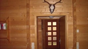Interior de una cabaña de madera con una puerta que da a otra habitación.